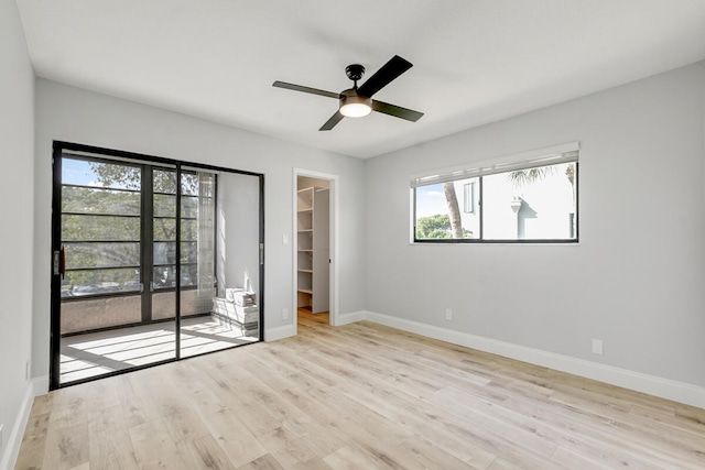 unfurnished bedroom with ceiling fan, light hardwood / wood-style floors, a spacious closet, and a closet