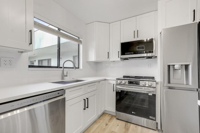 kitchen featuring sink, stainless steel appliances, light hardwood / wood-style flooring, backsplash, and white cabinets