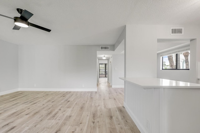 interior space featuring a textured ceiling, light hardwood / wood-style floors, and ceiling fan