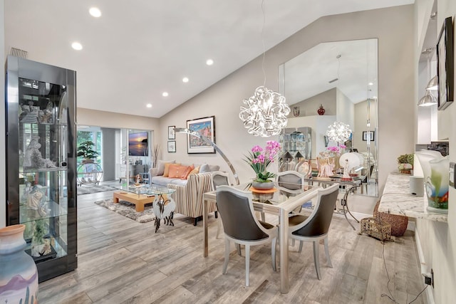 dining space with an inviting chandelier, vaulted ceiling, and light wood-type flooring