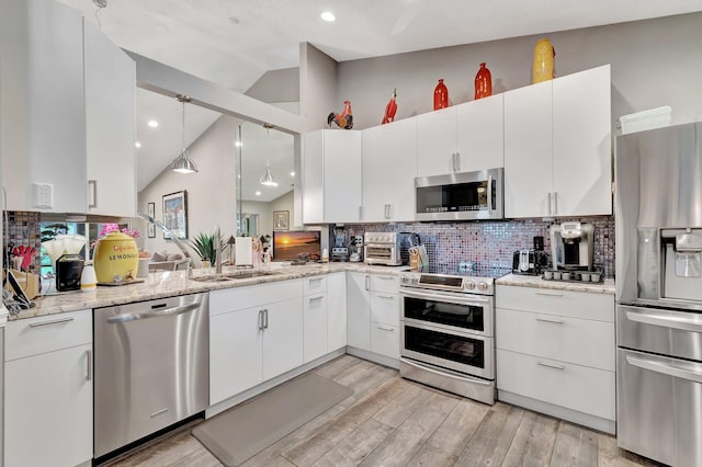 kitchen featuring backsplash, stainless steel appliances, vaulted ceiling, sink, and white cabinetry