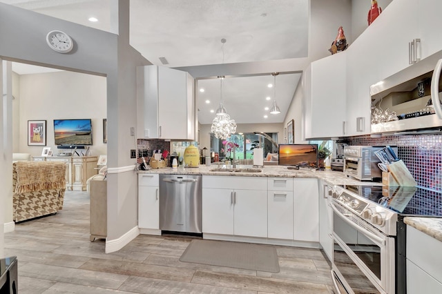 kitchen with appliances with stainless steel finishes, light stone counters, sink, white cabinetry, and hanging light fixtures