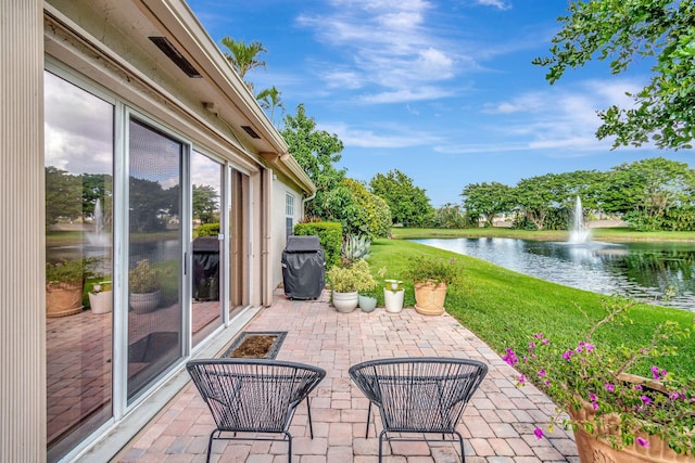 view of patio with area for grilling and a water view