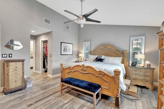 bedroom featuring a walk in closet, ceiling fan, a closet, and vaulted ceiling