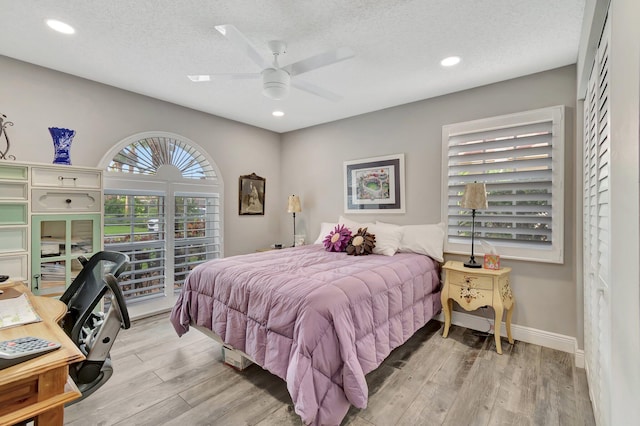 bedroom with ceiling fan, a textured ceiling, and light wood-type flooring