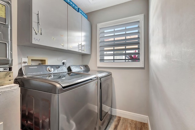 washroom with washer and dryer, hardwood / wood-style flooring, and cabinets