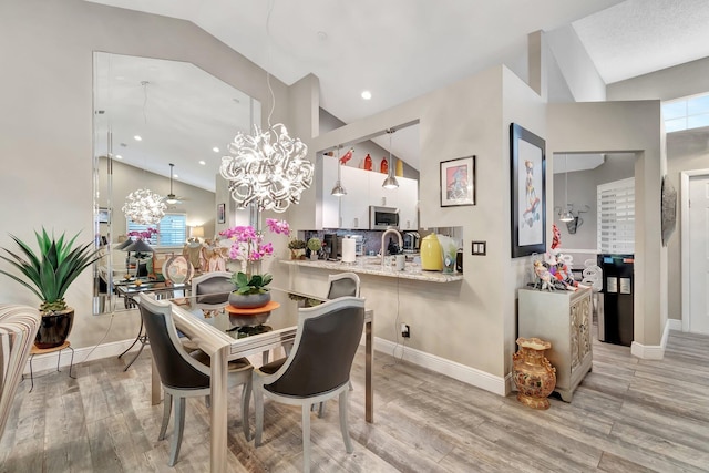 dining space with a notable chandelier, light hardwood / wood-style flooring, and vaulted ceiling