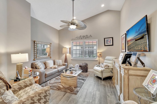 living room featuring ceiling fan, light hardwood / wood-style floors, and high vaulted ceiling