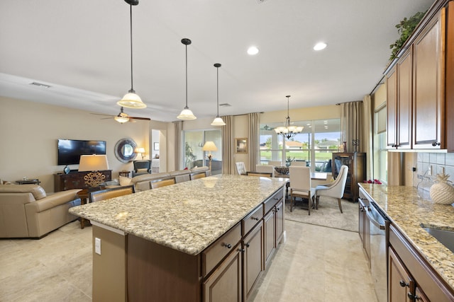 kitchen featuring dishwasher, a kitchen island, light stone countertops, and hanging light fixtures