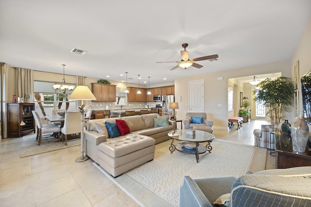 tiled living room with ceiling fan with notable chandelier