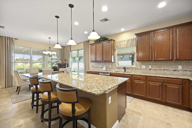 kitchen featuring hanging light fixtures, decorative backsplash, sink, a breakfast bar area, and a center island