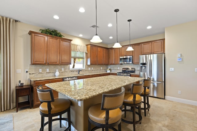 kitchen featuring stainless steel appliances, light stone counters, tasteful backsplash, hanging light fixtures, and a center island