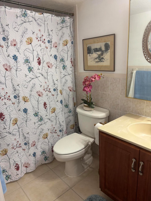 bathroom featuring toilet, vanity, tile walls, and tile patterned floors