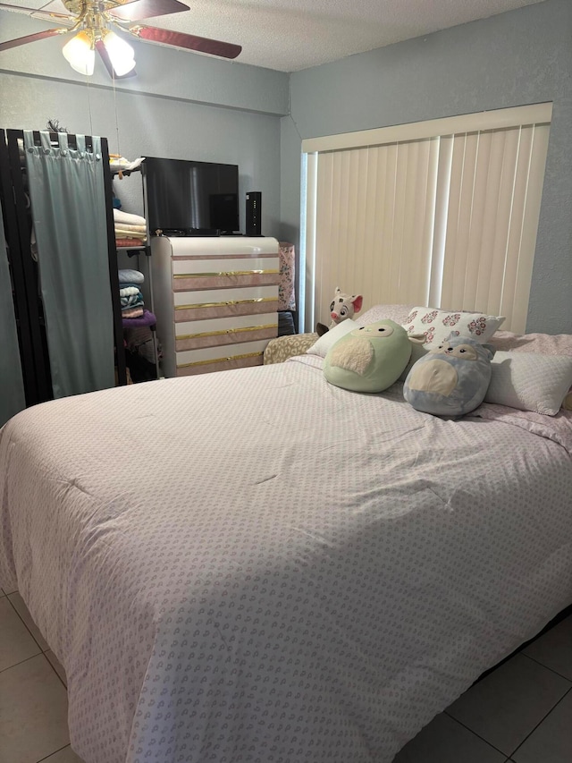 tiled bedroom with a textured ceiling and ceiling fan