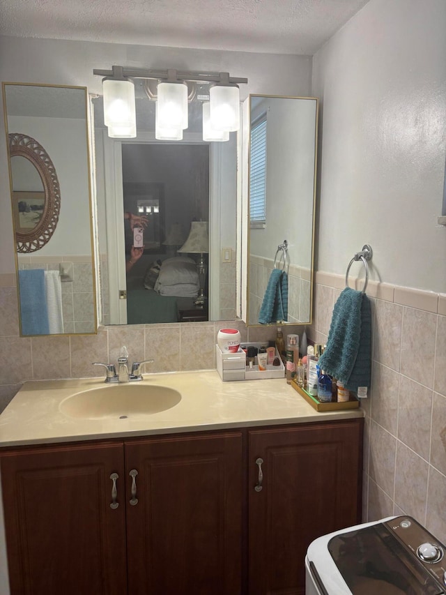 bathroom featuring washer / dryer, vanity, and tile walls