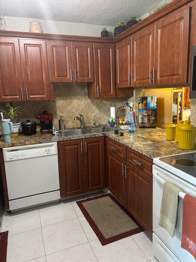 kitchen featuring decorative backsplash, light tile patterned floors, a textured ceiling, sink, and white appliances