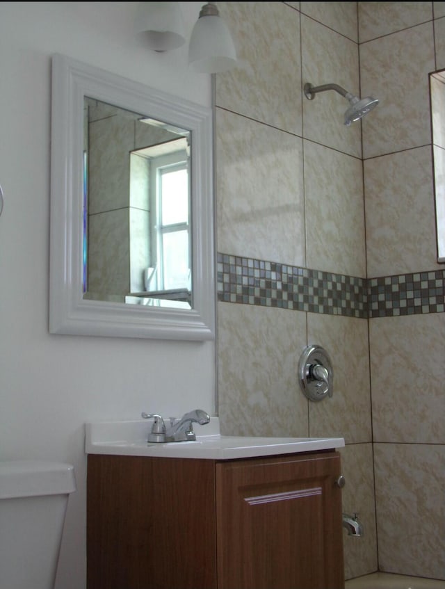 full bathroom with toilet, vanity, and tiled shower / bath