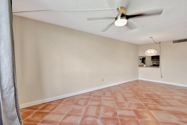 empty room featuring tile patterned flooring, a textured ceiling, and ceiling fan