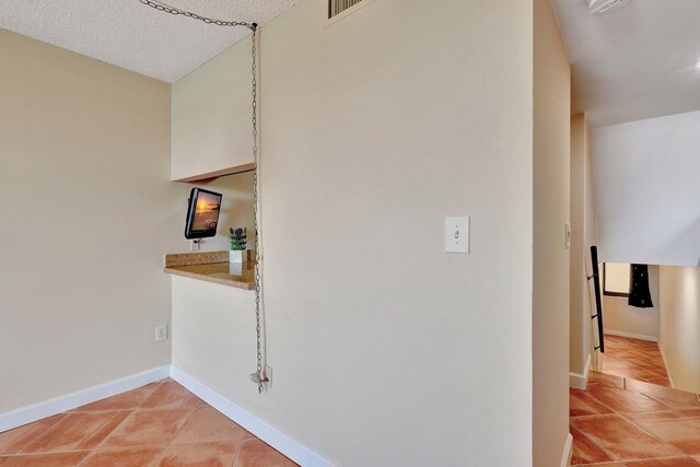 corridor featuring light tile patterned floors and a textured ceiling