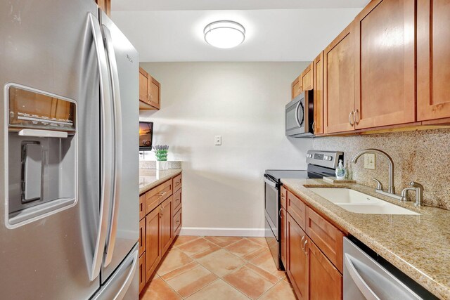 kitchen with backsplash, sink, light tile patterned floors, appliances with stainless steel finishes, and light stone counters