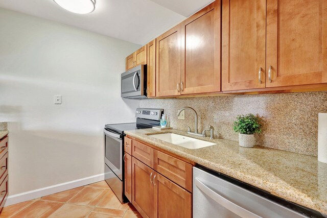 kitchen with light stone countertops, sink, backsplash, light tile patterned floors, and appliances with stainless steel finishes