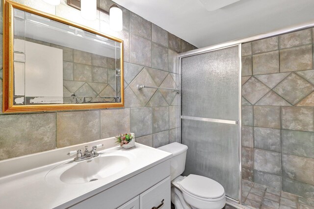 bathroom featuring vanity, an enclosed shower, tile walls, and toilet