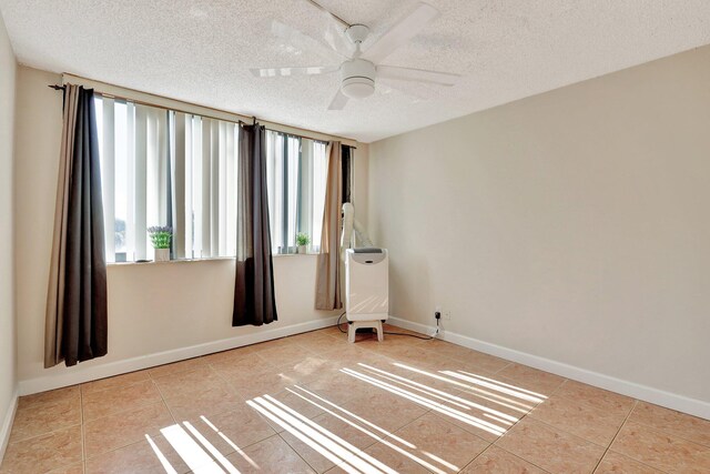 tiled empty room featuring ceiling fan and a textured ceiling