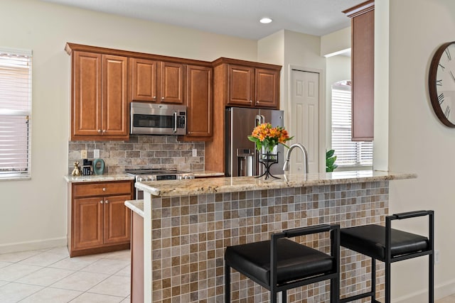 kitchen featuring kitchen peninsula, stainless steel appliances, a breakfast bar area, and tasteful backsplash