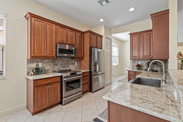 kitchen featuring light stone counters, sink, light tile patterned floors, and stainless steel appliances