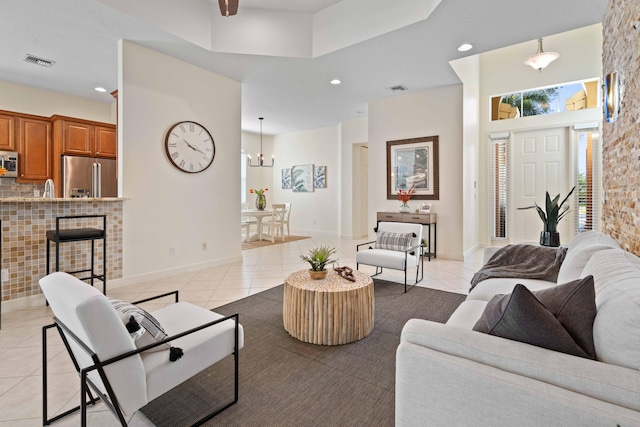 living room featuring light tile patterned floors, a towering ceiling, and an inviting chandelier