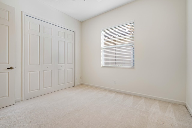 unfurnished bedroom with a closet and light colored carpet