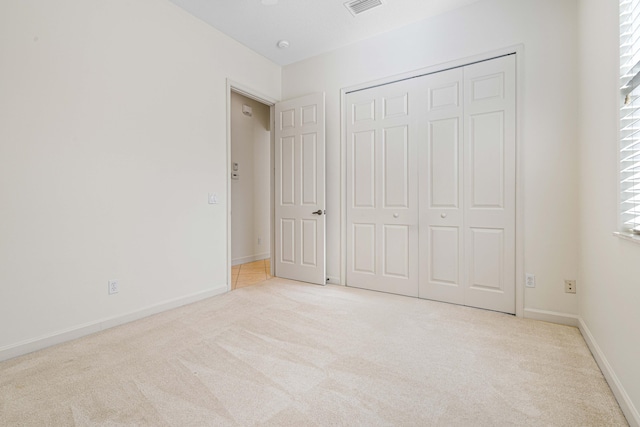 unfurnished bedroom featuring light colored carpet and a closet