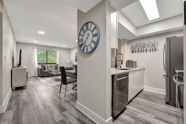 kitchen featuring light stone countertops, appliances with stainless steel finishes, sink, and wood-type flooring