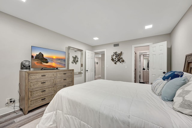 bedroom featuring ensuite bathroom and light wood-type flooring