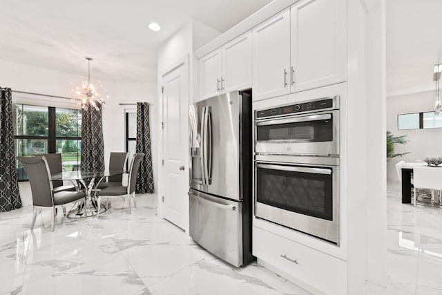 kitchen featuring stainless steel appliances, hanging light fixtures, white cabinets, and an inviting chandelier