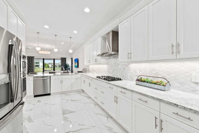 kitchen with decorative light fixtures, sink, white cabinets, stainless steel appliances, and wall chimney exhaust hood