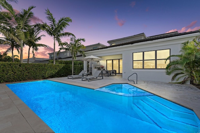 pool at dusk featuring a patio