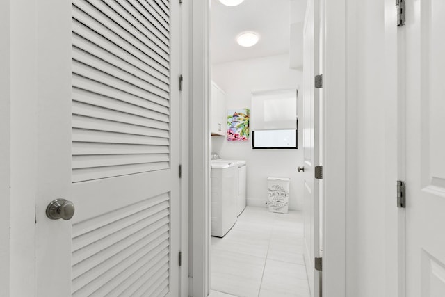 laundry area featuring cabinets, light tile patterned floors, and washer and clothes dryer