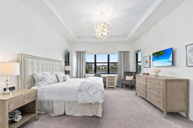 carpeted bedroom with an inviting chandelier and a raised ceiling