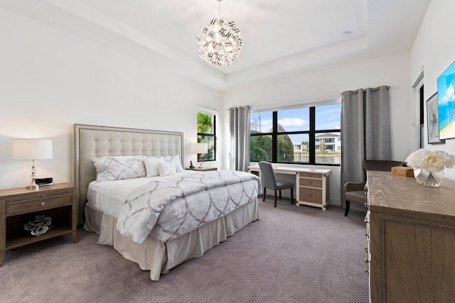 carpeted bedroom featuring a tray ceiling and a chandelier