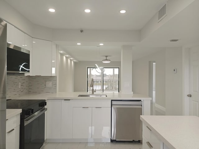 kitchen featuring sink, decorative light fixtures, decorative backsplash, white cabinets, and appliances with stainless steel finishes