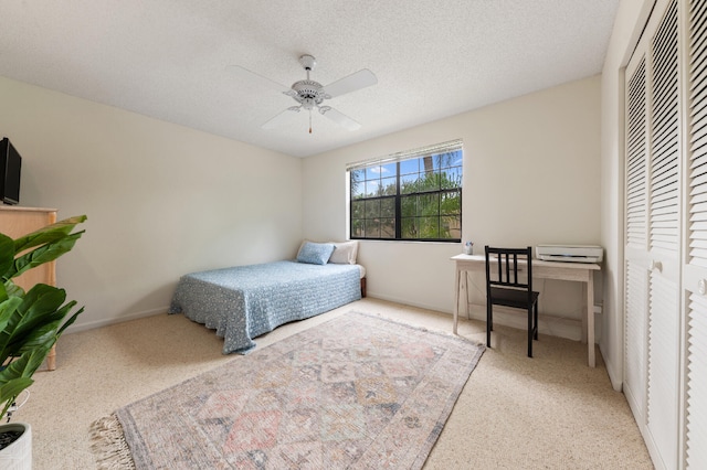 carpeted bedroom with a textured ceiling, a closet, and ceiling fan