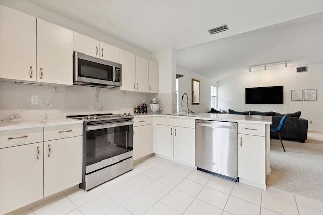 kitchen with sink, kitchen peninsula, decorative backsplash, white cabinets, and appliances with stainless steel finishes