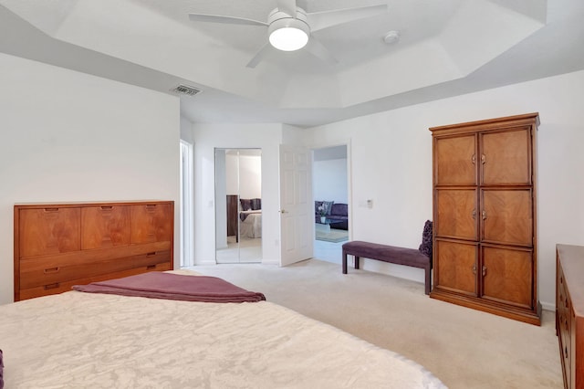 carpeted bedroom featuring ceiling fan and a tray ceiling