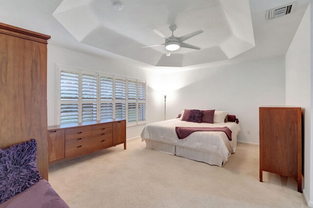 bedroom featuring light carpet, ceiling fan, and a raised ceiling