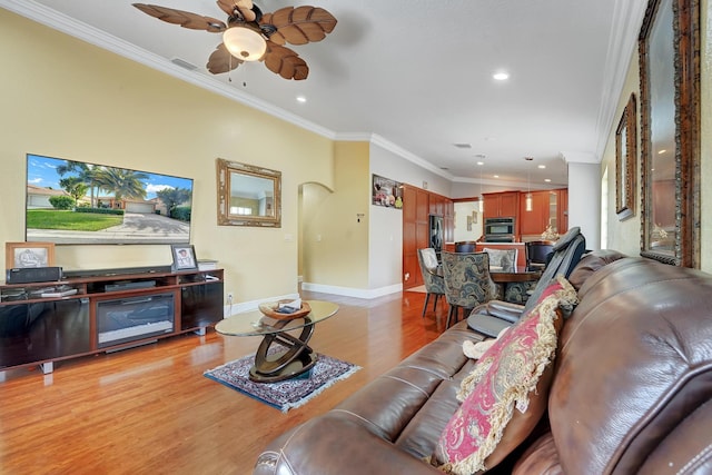 living room with ceiling fan, light wood-type flooring, and crown molding