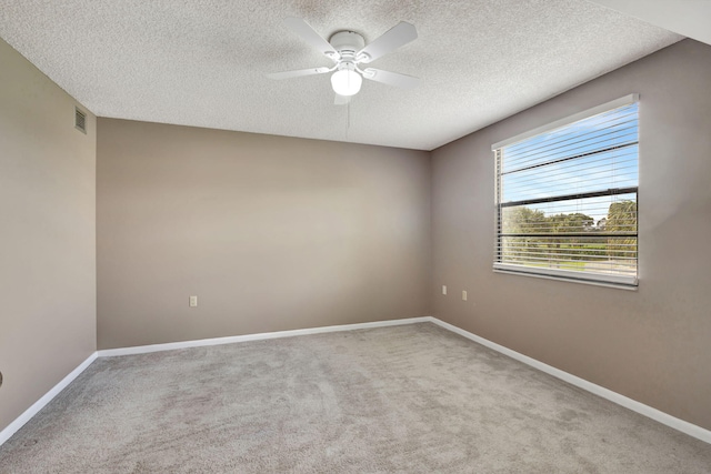 empty room with a textured ceiling, light colored carpet, and ceiling fan