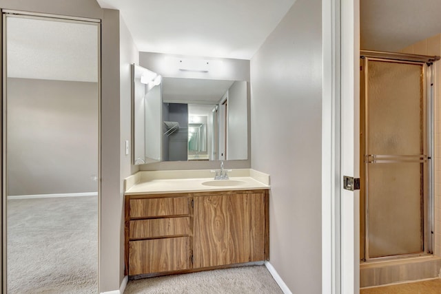 bathroom featuring a shower with shower door and vanity