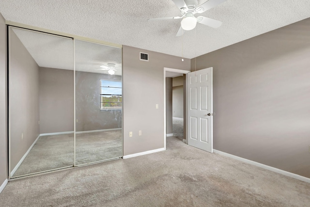 unfurnished bedroom with ceiling fan, a textured ceiling, a closet, and carpet floors