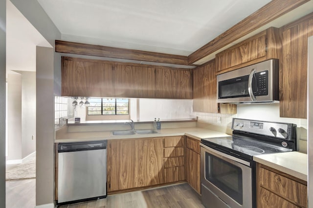 kitchen with light hardwood / wood-style floors, sink, backsplash, and appliances with stainless steel finishes